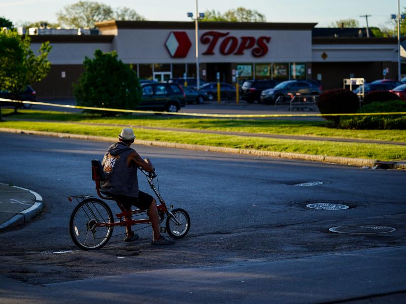 A cyclist pauses outside the site of the supermarket shooting in Buffalo, N.Y. With the Tops store closed for the foreseeable future, the community around it has been left without easy access to healthy and affordable food. A cyclist pauses outside the site of the supermarket shooting in Buffalo, N.Y. With the Tops store closed for the foreseeable future, the community around it has been left without easy access to healthy and affordable food.