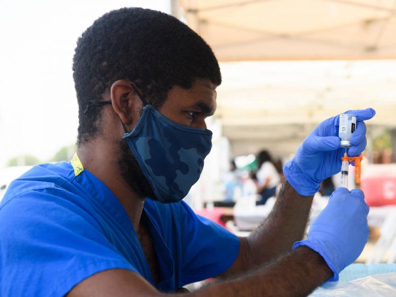 A health care worker prepares a dose of the Moderna COVID-19 vaccine during a clinic held at the Watts Juneteenth Street Fair in the Watts neighborhood of Los Angeles. A health care worker prepares a dose of the Moderna COVID-19 vaccine during a clinic held at the Watts Juneteenth Street Fair in the Watts neighborhood of Los Angeles.