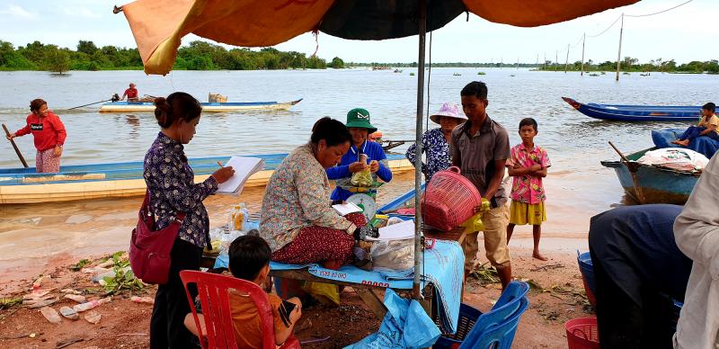 Fish broker Khout Phany, 39, (under umbrella) sits while fishermen bring their catch to be weighed in Chhnok Tru, a fishing village at the southern tip of the Tonle Sap lake where it meets the river. Fish broker Khout Phany, 39, (under umbrella) sits while fishermen bring their catch to be weighed in Chhnok Tru, a fishing village at the southern tip of the Tonle Sap lake where it meets the river.