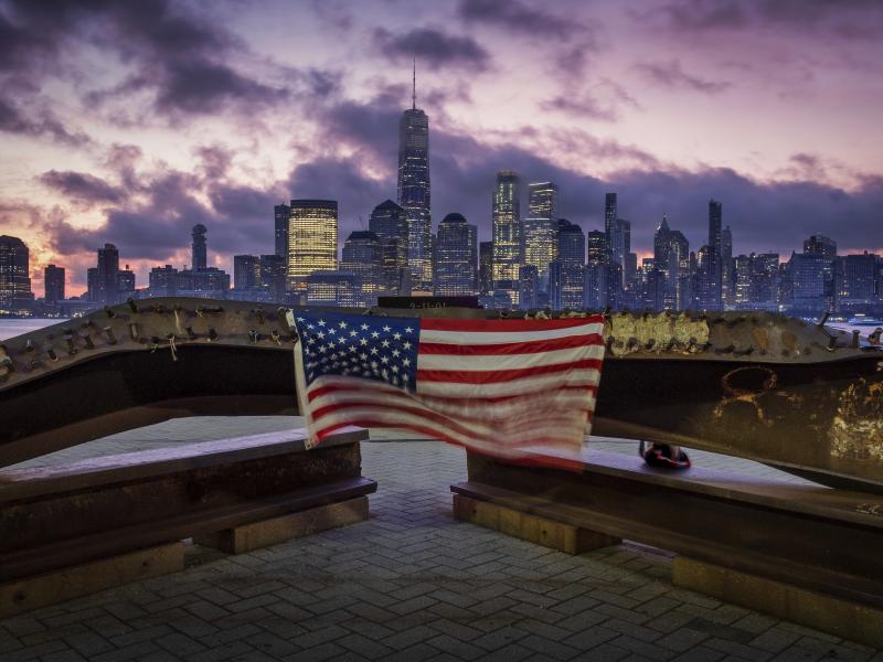A U.S. Flag hanging from a steal girder, damaged in the Sept. 11, 2001 attacks on the World Trade Center, blows in the breeze at a memorial in Jersey City, N.J., Sept. 11, 2019 as the sun rises behind the One World Trade Center building and the re-develop A U.S. Flag hanging from a steal girder, damaged in the Sept. 11, 2001 attacks on the World Trade Center, blows in the breeze at a memorial in Jersey City, N.J., Sept. 11, 2019 as the sun rises behind the One World Trade Center building and the re-develop