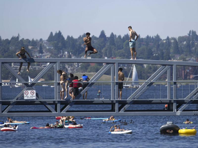 People jump from a pedestrian bridge at Lake Union Park in Seattle on Sunday as a record-setting heat wave blasts the Pacific Northwest. People jump from a pedestrian bridge at Lake Union Park in Seattle on Sunday as a record-setting heat wave blasts the Pacific Northwest.