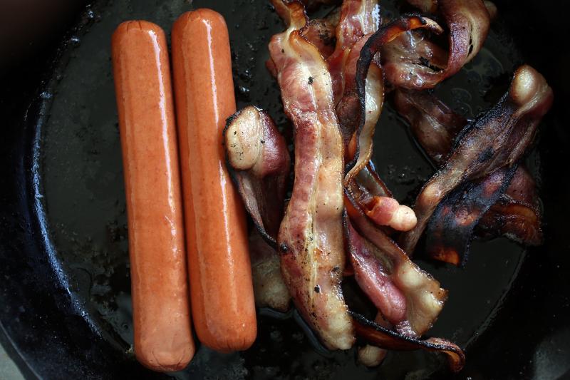 Processed meats, including hot dogs and bacon, cook in a frying pan. A new study of 80,000 people finds that those who ate the most red meat — especially processed meats such as bacon and hot dogs — had a higher risk of premature death compared with t Processed meats, including hot dogs and bacon, cook in a frying pan. A new study of 80,000 people finds that those who ate the most red meat — especially processed meats such as bacon and hot dogs — had a higher risk of premature death compared with t