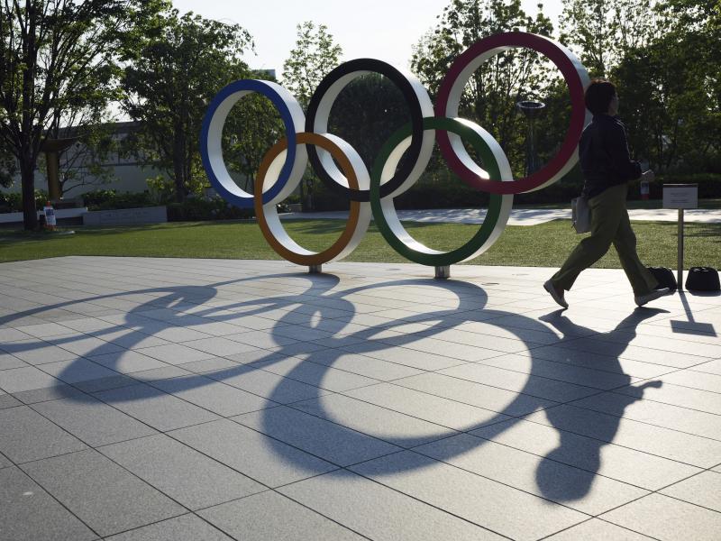 A woman passes the Olympic Rings near the National Stadium last month in Tokyo. There won't be any spectators at Olympic events in Japan's capital. A woman passes the Olympic Rings near the National Stadium last month in Tokyo. There won't be any spectators at Olympic events in Japan's capital.