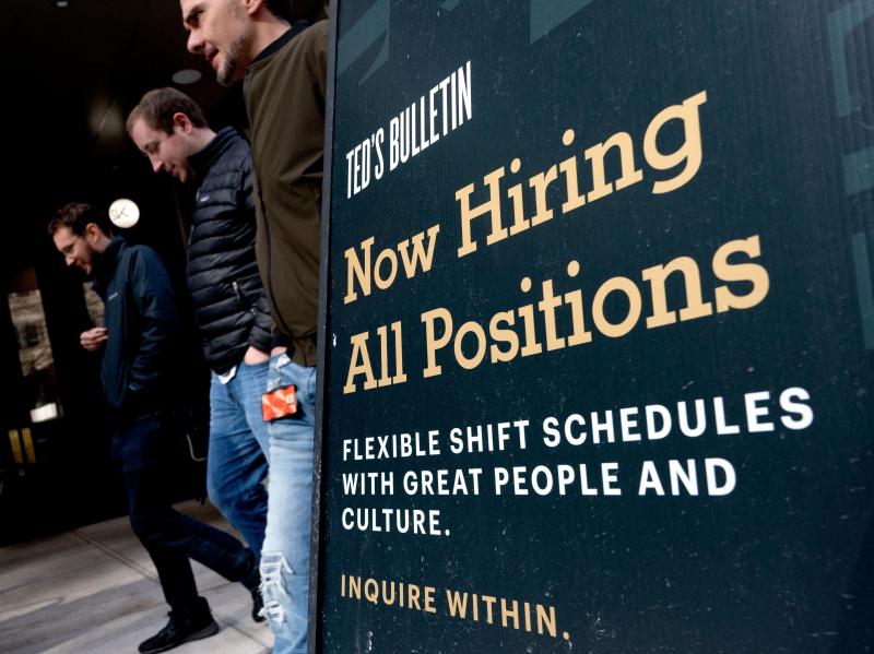 Pedestrians walk past a Now Hiring sign in Arlington, Va., on March 16. Pedestrians walk past a Now Hiring sign in Arlington, Va., on March 16.