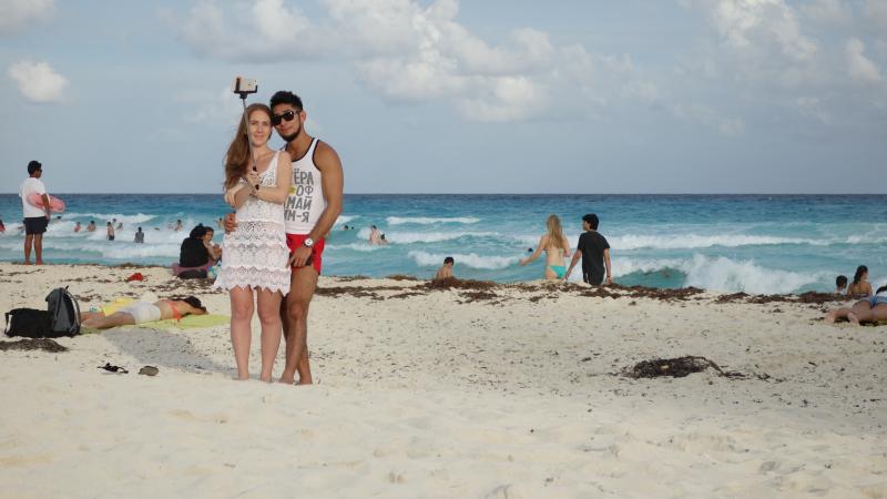 A couple uses a selfie stick on a Mexican beach. A couple uses a selfie stick on a Mexican beach.