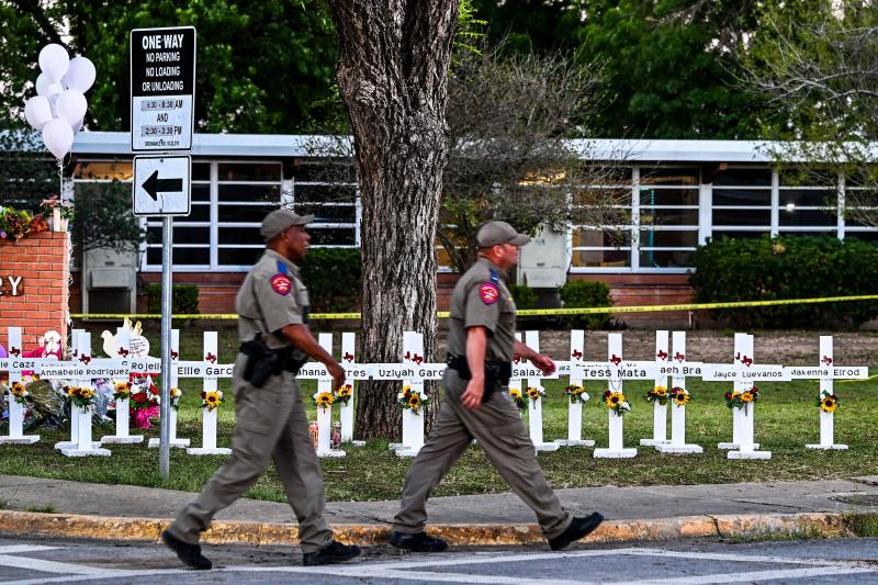 Police officers walk past a makeshift memorial for the shooting victims at Robb Elementary School in Uvalde, Texas, on Thursday. Police officers walk past a makeshift memorial for the shooting victims at Robb Elementary School in Uvalde, Texas, on Thursday.