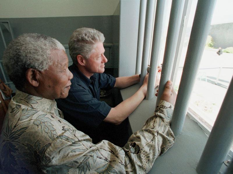 Nelson Mandela and former U.S. President Bill Clinton look to the outside from Mandela's Robben Island prison cell in Cape Town, South Africa, in this photo from March 27, 1998. Nelson Mandela and former U.S. President Bill Clinton look to the outside from Mandela's Robben Island prison cell in Cape Town, South Africa, in this photo from March 27, 1998.