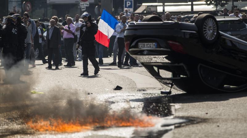 An UberPop vehicle was overturned by French taxi drivers, who also clashed with riot police, during Thursday's protest of the app-based ride-hailing company. An UberPop vehicle was overturned by French taxi drivers, who also clashed with riot police, during Thursday's protest of the app-based ride-hailing company.
