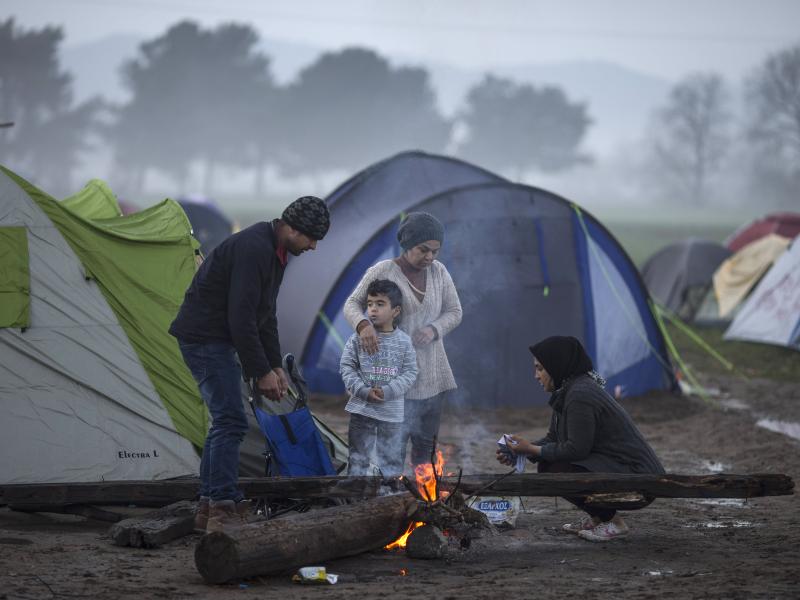 A family warms by a fire in the early morning on the Greek-Macedonia border on Tuesday in Idomeni, Greece. A family warms by a fire in the early morning on the Greek-Macedonia border on Tuesday in Idomeni, Greece.