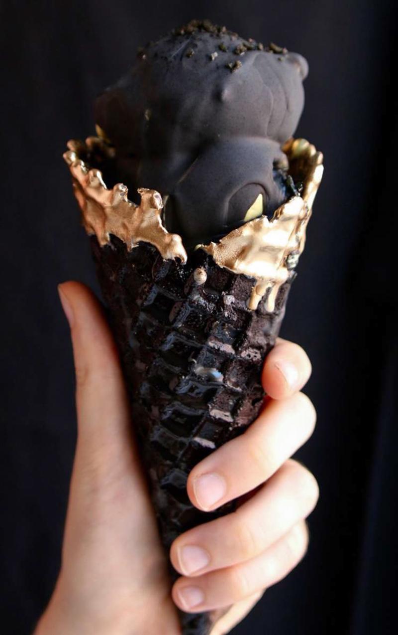 The Eclipse Magic Cone features a black waffle cone made with coconut ash and tipped with edible gold, and an interior filled with spiced marshmallow fluff and a golden-yellow ice cream flavored with ginger and turmeric. The Eclipse Magic Cone features a black waffle cone made with coconut ash and tipped with edible gold, and an interior filled with spiced marshmallow fluff and a golden-yellow ice cream flavored with ginger and turmeric.