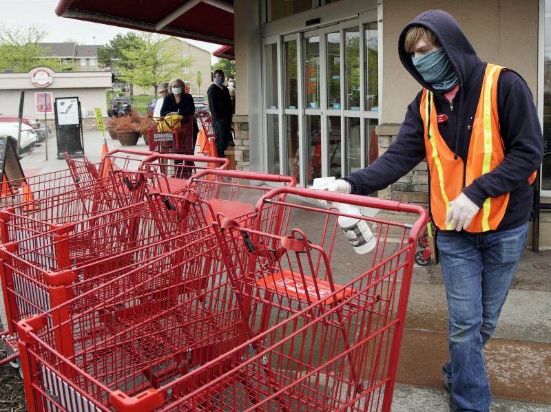 A Trader Joe's worker disinfects shopping carts and controls the number of customers allowed to shop at one time in Omaha, Neb., on May 7, 2020. Grocers like Trader Joe's are offering pay incentives to encourage their workers to get vaccinated against COV A Trader Joe's worker disinfects shopping carts and controls the number of customers allowed to shop at one time in Omaha, Neb., on May 7, 2020. Grocers like Trader Joe's are offering pay incentives to encourage their workers to get vaccinated against COV