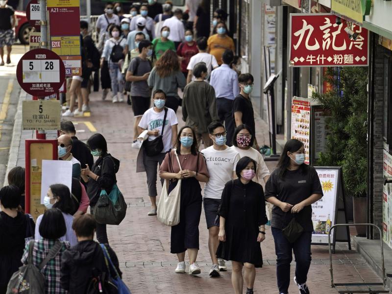 In this Oct. 9, 2020, photo, people walk down a street in Hong Kong. Singapore and Hong Kong have postponed a planned air travel bubble meant to boost tourism amid a spike in coronavirus infections in Hong Kong. In this Oct. 9, 2020, photo, people walk down a street in Hong Kong. Singapore and Hong Kong have postponed a planned air travel bubble meant to boost tourism amid a spike in coronavirus infections in Hong Kong.