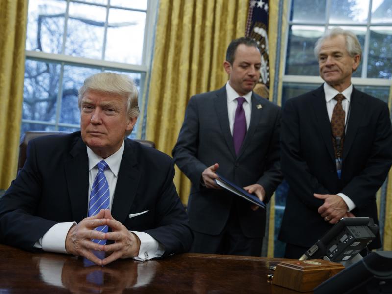 National Trade Council head Peter Navarro (right) and White House Chief of Staff Reince Priebus (center) await President Trump's signing executive orders at the White House on Jan. 23. National Trade Council head Peter Navarro (right) and White House Chief of Staff Reince Priebus (center) await President Trump's signing executive orders at the White House on Jan. 23.