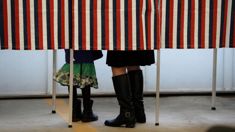 A woman is accompanied by a child inside a voting booth, as she casts her ballot in the New Hampshire presidential primary. A woman is accompanied by a child inside a voting booth, as she casts her ballot in the New Hampshire presidential primary.
