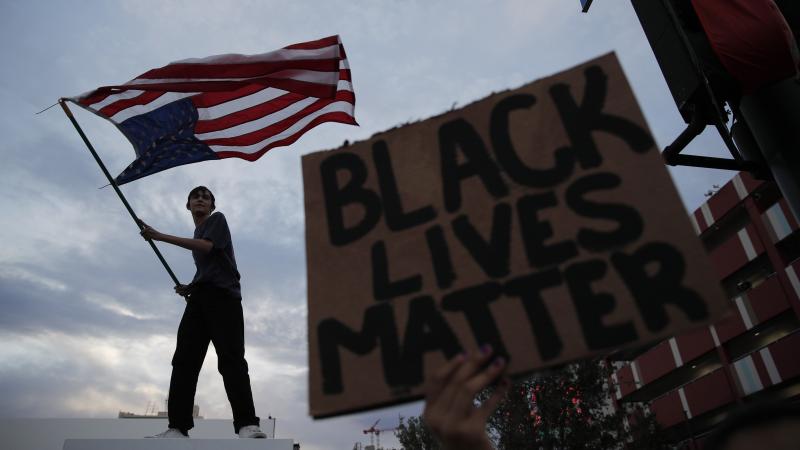 A man waves an upside-down American flag during a protest in Las Vegas following the death of George Floyd, a black man who died after a white Minneapolis police officer knelt on his neck. A man waves an upside-down American flag during a protest in Las Vegas following the death of George Floyd, a black man who died after a white Minneapolis police officer knelt on his neck.