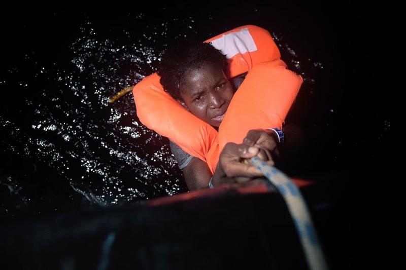 A migrant holds onto a rope during a rescue operation some eight nautical miles off Libya's Mediterranean coastline earlier this month. A migrant holds onto a rope during a rescue operation some eight nautical miles off Libya's Mediterranean coastline earlier this month.