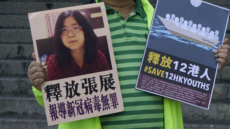 A pro-democracy activist holds placards with the picture of Chinese citizen journalist Zhang Zhan outside the Chinese central government's liaison office, in Hong Kong, Monday. Activists demand the release of Zhang, as well as the 12 Hong Kong activists d A pro-democracy activist holds placards with the picture of Chinese citizen journalist Zhang Zhan outside the Chinese central government's liaison office, in Hong Kong, Monday. Activists demand the release of Zhang, as well as the 12 Hong Kong activists d