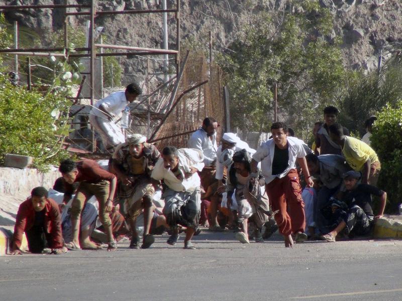 People seek shelter amid gunfire at an army base in Yemen's southern port city of Aden on Wednesday. People seek shelter amid gunfire at an army base in Yemen's southern port city of Aden on Wednesday.