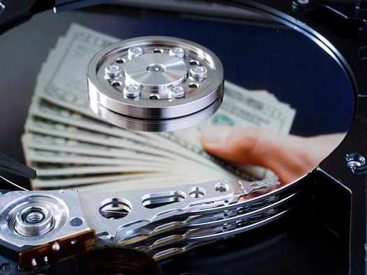 Dollar bills are reflected in a computer hard drive. Dollar bills are reflected in a computer hard drive.