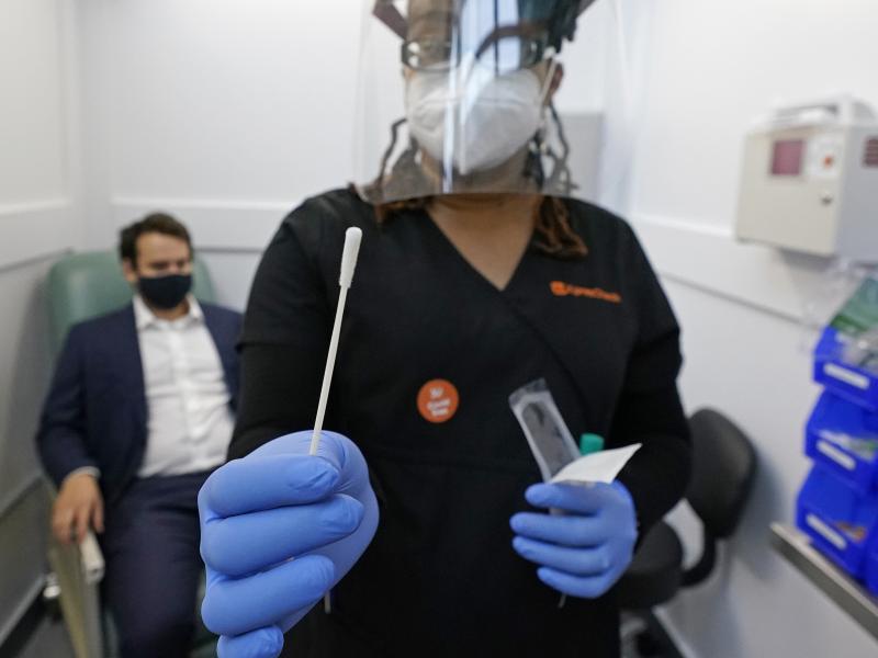 A medical assistant holds a swab after testing a man on Wednesday at the new COVID-19 testing facility at Boston Logan International Airport. A medical assistant holds a swab after testing a man on Wednesday at the new COVID-19 testing facility at Boston Logan International Airport.
