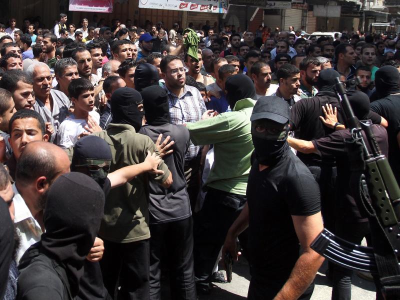Armed Palestinian masked militants push back a crowd of worshippers outside a mosque in Gaza City on August 22, 2014, before executing more than a dozen men for allegedly helping Israel during its six-week assault on the Palestinian enclave. This week, Am Armed Palestinian masked militants push back a crowd of worshippers outside a mosque in Gaza City on August 22, 2014, before executing more than a dozen men for allegedly helping Israel during its six-week assault on the Palestinian enclave. This week, Am