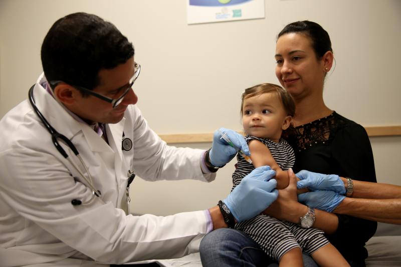 Daniela Chavarriaga holds her daughter Emma as Dr. Jose Rosa-Olivares administers a measles vaccination at Miami Children's Hospital. Daniela Chavarriaga holds her daughter Emma as Dr. Jose Rosa-Olivares administers a measles vaccination at Miami Children's Hospital.