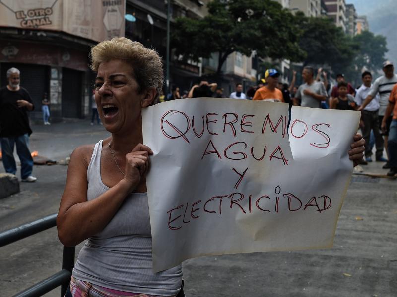 A woman holds a placard reading "We Want Water and Electricity" as she shouts slogans during a protest in Caracas, Venezuela, about a lack of water and electric service during a new power outage in the country on Sunday. President Nicolás Maduro announce A woman holds a placard reading "We Want Water and Electricity" as she shouts slogans during a protest in Caracas, Venezuela, about a lack of water and electric service during a new power outage in the country on Sunday. President Nicolás Maduro announce