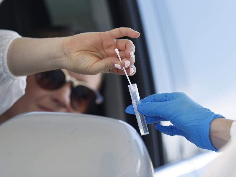 A woman drops a nasal swab in a vial at the announcement that Denver will launch a drive-up COVID-19 test site. A woman drops a nasal swab in a vial at the announcement that Denver will launch a drive-up COVID-19 test site.