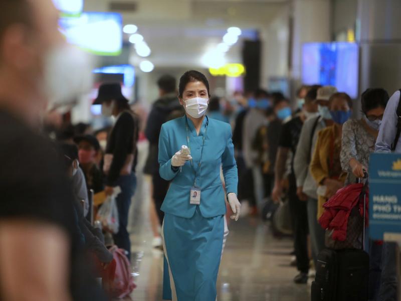 An airline employee holds a thermometer to check boarding passengers at Noi Bai International Airport in Hanoi, Vietnam. After three weeks with no local cases reported, Vietnam has reopened schools, businesses, factories and tourist attractions. An airline employee holds a thermometer to check boarding passengers at Noi Bai International Airport in Hanoi, Vietnam. After three weeks with no local cases reported, Vietnam has reopened schools, businesses, factories and tourist attractions.
