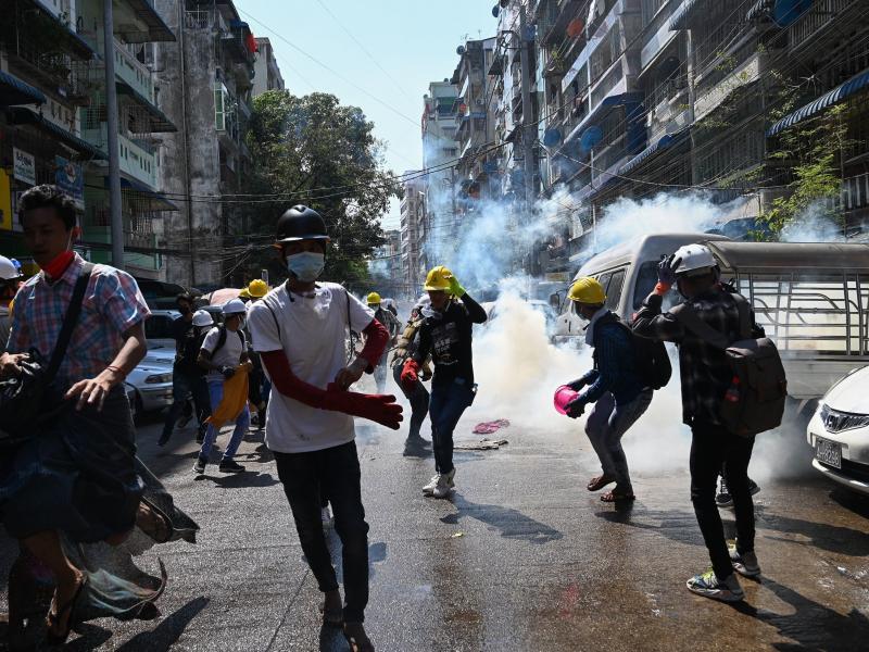 Protesters in Yangon run from police Sunday after they fire tear gas during a demonstration against the military coup. Protesters in Yangon run from police Sunday after they fire tear gas during a demonstration against the military coup.