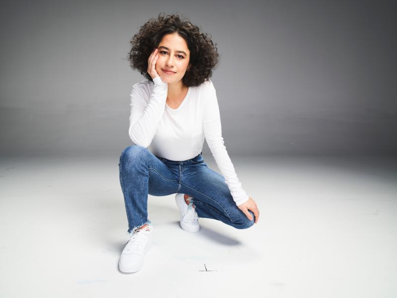 Ilana Glazer kneels in a white shirt and blue jeans Ilana Glazer kneels in a white shirt and blue jeans