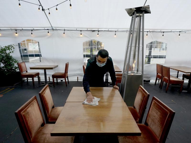 A person cleans a table in an outdoor tented dining area of a restaurant in Sacramento, Calif., on Nov. 19. Job growth slowed sharply in November as relief aid is due to expire at the end of the year. A person cleans a table in an outdoor tented dining area of a restaurant in Sacramento, Calif., on Nov. 19. Job growth slowed sharply in November as relief aid is due to expire at the end of the year.
