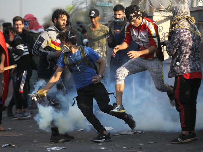 An Iraqi protester grabs a tear gas canister fired by riot police amid clashes following a demonstration east of Tahrir Square, on Monday. An Iraqi protester grabs a tear gas canister fired by riot police amid clashes following a demonstration east of Tahrir Square, on Monday.