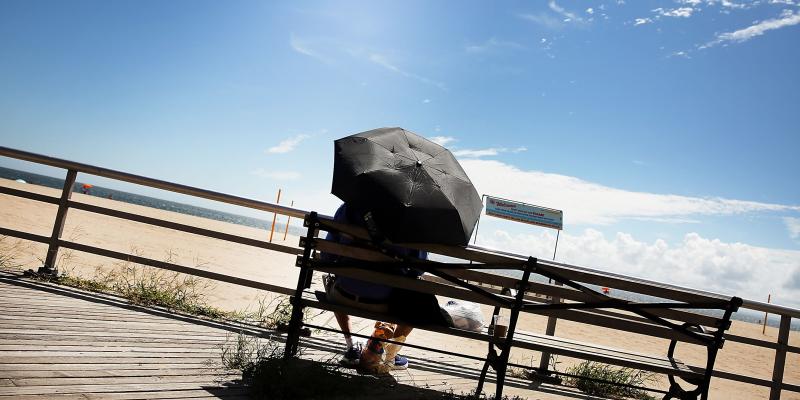 A man finds a bit of shade on the boardwalk at Brighton Beach in New York City. A man finds a bit of shade on the boardwalk at Brighton Beach in New York City.