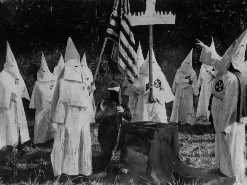 Members of the Ku Klux Klan ceremonially initiate a new recruit at a meeting in 1922. Members of the Ku Klux Klan ceremonially initiate a new recruit at a meeting in 1922.
