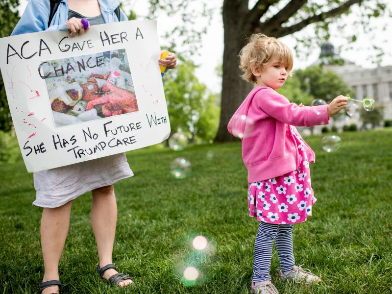 Charlie Wood of Charlottesville, Va., plays with bubbles during a May 4, 2017, rally near the Capitol to oppose proposed changes to the Affordable Care Act. Charlie was born a few months prematurely, and her mother, Rebecca (left), fears changes to the he Charlie Wood of Charlottesville, Va., plays with bubbles during a May 4, 2017, rally near the Capitol to oppose proposed changes to the Affordable Care Act. Charlie was born a few months prematurely, and her mother, Rebecca (left), fears changes to the he