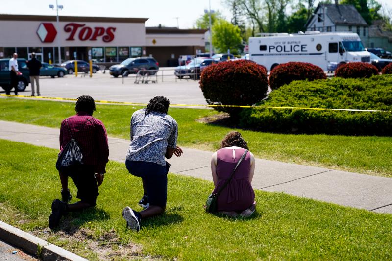 People pray outside the scene of a shooting at a supermarket, in Buffalo, N.Y., on Sunday. A day earlier, a white 18-year-old killed 10 people and wounded three in what authorities described as "racially motivated violent extremism." People pray outside the scene of a shooting at a supermarket, in Buffalo, N.Y., on Sunday. A day earlier, a white 18-year-old killed 10 people and wounded three in what authorities described as "racially motivated violent extremism."