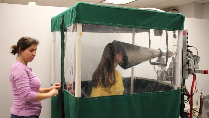 Undergraduate Shira Rubin gamely demonstrates the Gesundheit machine, which collects samples of virus from the breath that sick students exhale. Rubin helps Dr. Somayeh Youssefi (left) set up the machine before patients use it. Undergraduate Shira Rubin gamely demonstrates the Gesundheit machine, which collects samples of virus from the breath that sick students exhale. Rubin helps Dr. Somayeh Youssefi (left) set up the machine before patients use it.