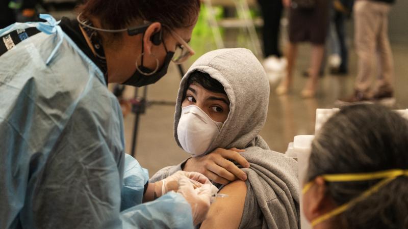 A student looks back at his mother, as he is vaccinated at a school-based COVID-19 vaccination clinic for students 12 and older in San Pedro, Calif., last month. A student looks back at his mother, as he is vaccinated at a school-based COVID-19 vaccination clinic for students 12 and older in San Pedro, Calif., last month.