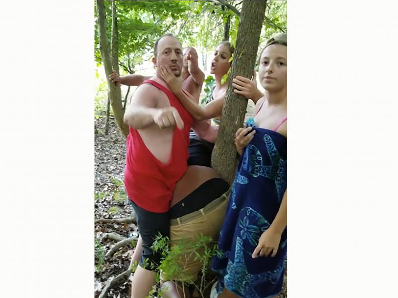 A group of white people surround Vauhxx Booker, center, as he is bent over leaning against a tree, at Monroe Lake near Bloomington, Ind., on July 4. A group of white people surround Vauhxx Booker, center, as he is bent over leaning against a tree, at Monroe Lake near Bloomington, Ind., on July 4.