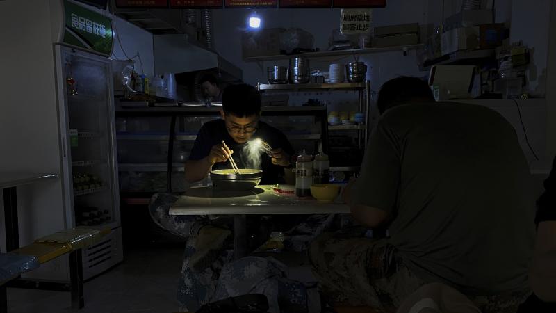A man uses his smartphone flashlight to light up his bowl of noodles as he eats breakfast at a restaurant during a blackout in Shenyang, in northeastern China's Liaoning province, Wednesday. People ate breakfast by flashlight and shopkeepers used portable A man uses his smartphone flashlight to light up his bowl of noodles as he eats breakfast at a restaurant during a blackout in Shenyang, in northeastern China's Liaoning province, Wednesday. People ate breakfast by flashlight and shopkeepers used portable