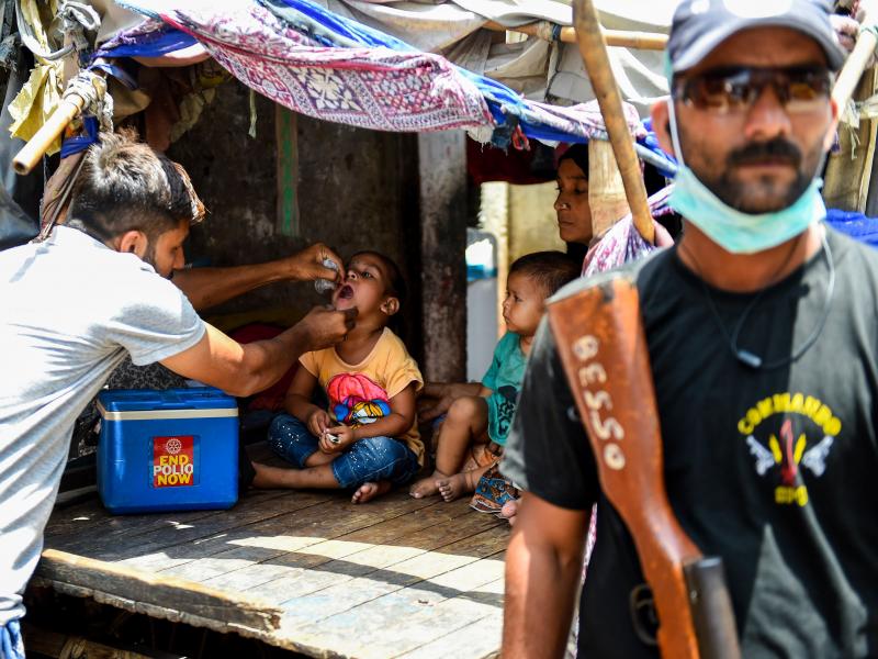 A Pakistani health worker administers the oral polio vaccine to a child during a campaign in Karachi on May 7. Because of past attacks on vaccinators, security personnel are often assigned to accompany them. A Pakistani health worker administers the oral polio vaccine to a child during a campaign in Karachi on May 7. Because of past attacks on vaccinators, security personnel are often assigned to accompany them.