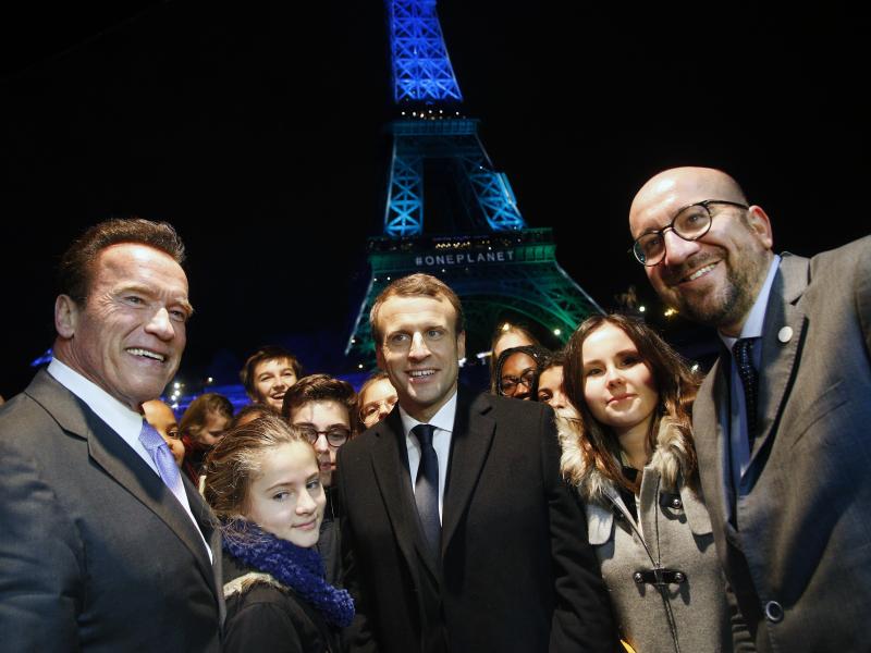 France's President Emmanuel Macron, center, Arnold Schwarzenegger, left, and Prime Minister of Belgium Charles Michel, right, pose for a photo in front of the Eiffel Tower while aboard a boat cruising on the Seine River after the One Planet Summit, Paris, France's President Emmanuel Macron, center, Arnold Schwarzenegger, left, and Prime Minister of Belgium Charles Michel, right, pose for a photo in front of the Eiffel Tower while aboard a boat cruising on the Seine River after the One Planet Summit, Paris,