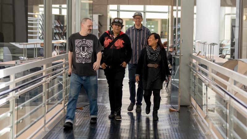 Leah Esguerra (right), who is credited with being the first social worker installed directly at a public library, strolls through the fifth floor of the San Francisco Public Library's main branch, joined by the library's health and safety associates (from Leah Esguerra (right), who is credited with being the first social worker installed directly at a public library, strolls through the fifth floor of the San Francisco Public Library's main branch, joined by the library's health and safety associates (from