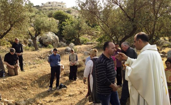 Ibrahim Shomali, a Palestinian priest, offers Communion under the olive trees of the Cremisan Valley in the Israeli-occupied West Bank. This is part of a regular protest against Israeli plans to build a section of its West Bank barrier here, which would s Ibrahim Shomali, a Palestinian priest, offers Communion under the olive trees of the Cremisan Valley in the Israeli-occupied West Bank. This is part of a regular protest against Israeli plans to build a section of its West Bank barrier here, which would s