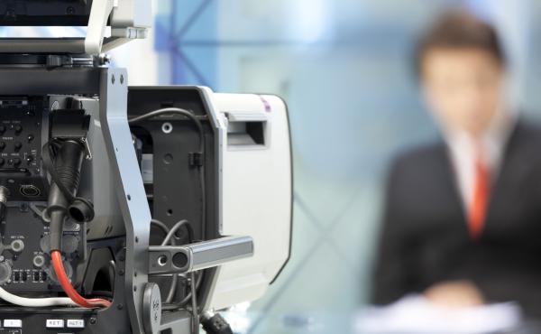 Newsreader in front of television camera. Newsreader in front of television camera.