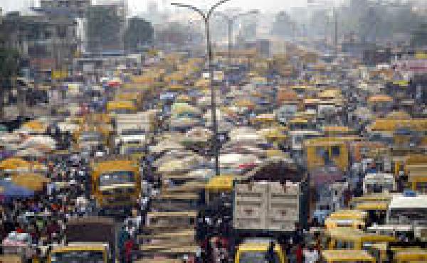 People walk struggling for space between public transport buses and trucks at the burstling Oshodi bus stop in Lagos 06 February 2006. Lagos is reputed as one of the mostly densely populated city in the world with population more than 14 million. AFP PHOT People walk struggling for space between public transport buses and trucks at the burstling Oshodi bus stop in Lagos 06 February 2006. Lagos is reputed as one of the mostly densely populated city in the world with population more than 14 million. AFP PHOT