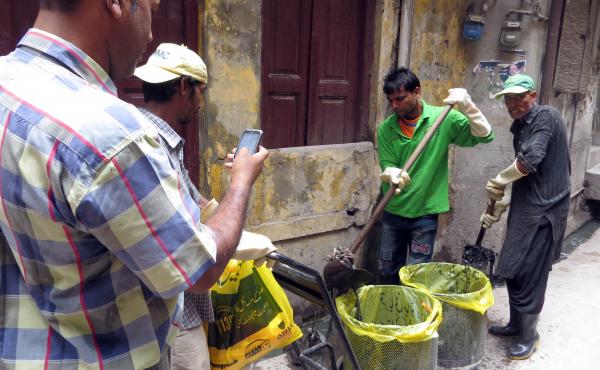 Inspector Mohammad Saleem Taqi takes a photo of sanitation workers as they clear out debris in sewers. The government feeds the photos into a map to track the city's effort to stop dengue fever. Inspector Mohammad Saleem Taqi takes a photo of sanitation workers as they clear out debris in sewers. The government feeds the photos into a map to track the city's effort to stop dengue fever.