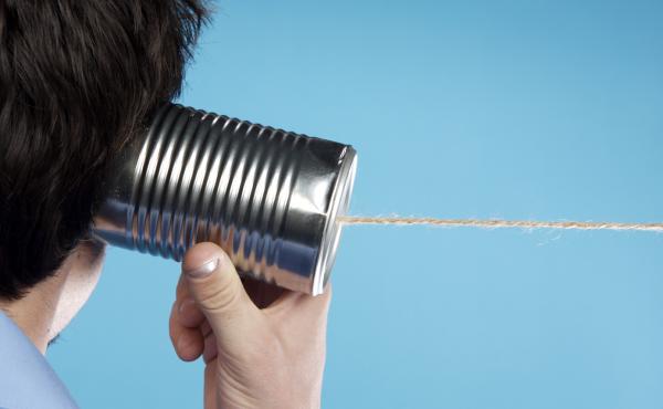 A man listens to a tin can telephone. A man listens to a tin can telephone.