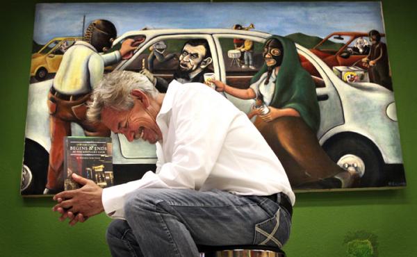 Author Benjamin Alire Saenz writes about life on the U.S.-Mexico border. Here he holds his latest book, Everything Begins and Ends at the Kentucky Club, in front of "$26," a painting by Francisco Delgado (the presidents in the painting appear on American Author Benjamin Alire Saenz writes about life on the U.S.-Mexico border. Here he holds his latest book, Everything Begins and Ends at the Kentucky Club, in front of "$26," a painting by Francisco Delgado (the presidents in the painting appear on American